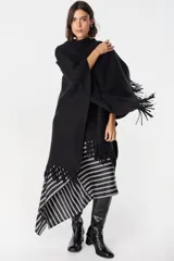 Ruana de tejido suave y envolvente en color blanco, con diseño de corte amplio y terminación de flecos en el ruedo.