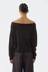 Buzo de punto fino color marrón oscuro, con escote bote amplio tipo off-the-shoulder, hombros caídos y mangas largas con puños y bajo acanalados.