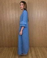 Vestido largo tipo túnica de color azul con estampado a cuadros blancos, cuello mao con escote en V y botones frontales parciales. Presenta mangas tres cuartos con volados en cascada.