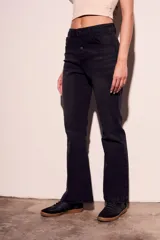 Pantalón de jean negro de corte flare con tiro medio y cierre frontal con botones.