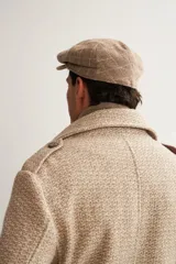 Boina con visera de lana fina uruguaya natural, sin teñir, con diseño de tejido texturizado en tonos beige y marrón.