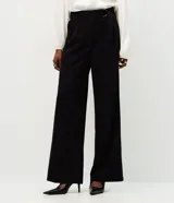 Pantalón de corte wide leg confeccionado en crepé color bordó, con cintura alta, cierre frontal con cremallera y detalle de hebilla ajustable en la cintura.