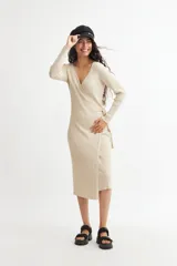 Vestido midi color crema, tejido en punto acanalado, con escote cruzado en V, mangas largas y lazo ajustable en la cintura.