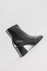 Botas plateadas de cuero con caña media, cierre lateral con cremallera, punta cuadrada y tacón geométrico de madera.