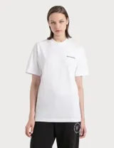 Remera blanca de algodón con cuello redondo y mangas cortas. Estampado pequeño con el logo de la marca 'Sporty & Rich' en el pecho y estampado grande en la parte inferior con el logo circular de la marca y la frase 'Health Is Wealth'.