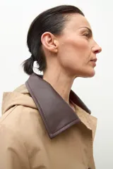 Trench impermeable color beige con cuello camisero en contraste de color marrón oscuro. Presenta cierre frontal con botones, bolsillos delanteros con solapa y mangas largas.