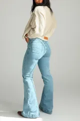 Pantalón de jean azul claro de tiro alto, con corte ajustado en la parte superior y botamanga acampanada. Presenta costuras reforzadas y bolsillos traseros clásicos.