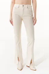 Jean color crudo de tiro medio/alto, silueta levemente acampanada desde la rodilla y tajo en el frente de la pierna.