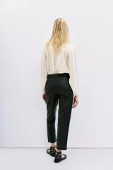 Pantalon de corte recto confeccionado en cuero ovino con acabado metalizado en color plata. Presenta cierre frontal con cremallera y bolsillos laterales.