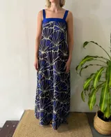 Vestido azul con estampado abstracto en blanco y azul oscuro. Presenta un escote cuadrado, tirantes anchos y un aplique de tafeta azul en el escote.