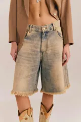 Bermuda de denim con efecto acid wash y lavado desgastado en tonos beige y celeste, de calce ancho y relajado, con largo a la rodilla y ruedo deshilachado.