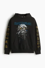 Canguro negro de corte oversized con capucha, bolsillo frontal tipo canguro y estampado frontal de la banda Iron Maiden con diseño de momia. Las mangas presentan detalles estampados en color dorado con motivos egipcios.