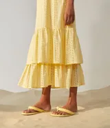 Vestido midi amarillo de algodón con tejido laise (ojales), escote cuadrado y tirantes ajustables con lazo. Presenta un diseño escalonado con volados en la falda.