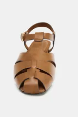 Sandalias estilo cangrejera plana de color marrón, con diseño de tiras entrelazadas en la parte delantera y cierre ajustable mediante hebilla metálica en el tobillo.