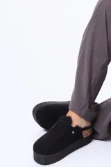 Sueco de plataforma color negro, con exterior de gamuza, interior forrado en piel sintética y detalle de corcho en el talón. Cuenta con una tira ajustable con broche metálico en el empeine.