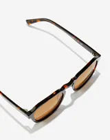 Lentes de sol Hawkers X Paula Echevarría, unisex, con montura geométrica color carey y lentes color marrón.