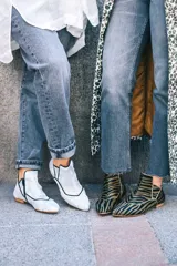 Botín de piel color plata con acabado texturizado y ribetes en contraste color negro. Presenta un diseño de caña baja con corte asimétrico y cierre lateral. Cuenta con suela de cuero y tacón bajo.