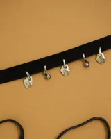 Gargantilla tipo choker de gamuza con dijes colgantes artesanales de metal y perlas naturales. Cuenta con tiras largas para atar y ajustar en la parte posterior.
