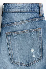 Short de denim de tiro superalto y corte clásico con cinco bolsillos, confeccionado en algodón rígido. Presenta detalles de roturas y efecto desgastado en la parte frontal, además de bajos deshilachados con flecos.