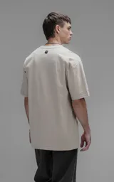 Remera de corte relajado con hombros caídos y silueta amplia, confeccionada en algodón premium. Presenta cuello redondo y mangas cortas, ofreciendo un calce cómodo y versátil.