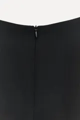 Vestido largo negro de tejido fluido, con cuello redondo, mangas cortas con dobladillo y cierre trasero con cremallera oculta.