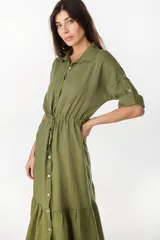 Vestido camisero largo de lino italiano color celeste, de corte relajado, con mangas caídas, jareta ajustable en la cintura, cierre frontal de botones y bajo con volado fruncido.