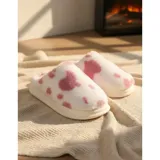 Pantuflas sin talón confeccionadas en algodón afelpado y piel sintética, con divertido estampado de manchas de vaca en tonos blanco y marrón, y suela de PVC.