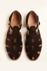 Sandalias de gamuza color marrón, estilo romano con diseño en T, tiras con aberturas laterales y cierre de hebilla metálica en el tobillo. Cuenta con tacón bajo de madera.