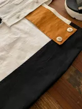 Minifalda blanca con aplique de cuero marrón con botones plateados.