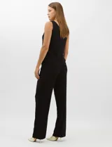 Conjunto de tres piezas compuesto por una musculosa negra con escote en V, un pantalón palazzo de tejido de punto liso con cintura elástica y una túnica larga de tul negro con mangas 3/4. La túnica presenta un bordado floral detallado con aplicaciones de lentejuelas.