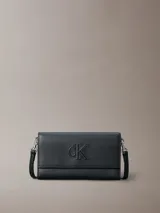 Billetera tipo sobre de Calvin Klein, color negro, confeccionada en piel sintética. Presenta el logo 'ck' grabado en el frente, cierre con solapa y correa desmontable, permitiendo su uso como cartera pequeña o clutch.
