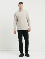 Remera de punto canalé francés con cuello polo, manga larga y cierre frontal de metal con tirador personalizado.