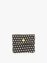 Monedero pequeño estilo sobre, confeccionado en cuero negro con estampado de lunares blancos. Posee un cierre frontal con broche a presión metálico de color dorado.