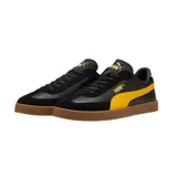 Championes Puma modelo Club Li Era, con diseño de perfil bajo en color negro, franja lateral blanca característica de la marca y suela de goma color caramelo. Presenta detalles en dorado en el logo lateral y la lengüeta.