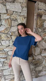 Blusa de manga corta color azul oscuro con textura arrugada o plisada, cuello redondo con borde festoneado.