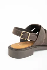 Sandalia tipo cangrejera de cuero marrón oscuro, con puntera cerrada tejida con tiras anchas y talón descubierto con tira ajustable y hebilla metálica. Posee suela de goma oscura y plantilla de cuero color camel con la marca grabada.