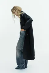 Abrigo largo de corte recto confeccionado en mezcla de lana. Presenta cuello con solapas de muesca, cierre frontal cruzado con doble botonadura y bolsillos laterales de vivo.