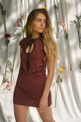 Vestido corto marrón con mangas cortas, escote redondo y abertura frontal con tiras ajustables. Presenta diseño entallado con drapeados sutiles.