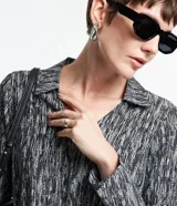 Vestido corto camisero de crepé con estampado abstracto en blanco y negro, cuello con solapa, mangas largas y lazo en la cintura.