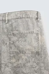 Pantalón de corte relajado confeccionado en tejido ligero de algodón con estampado abstracto de efecto lavado. Presenta cintura elástica, bolsillos frontales y bolsillos traseros de plastrón, con cierre frontal de cremallera y botón.