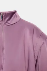 Chaqueta acolchada de cuello subido con cierre frontal de cremallera, manga larga con hombros marcados y puños elásticos. Presenta un diseño con bajo elástico y acabado satinado.