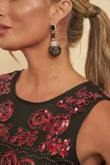 Aros colgantes tipo racimo, compuestos por una piedra negra superior rectangular rodeada de circones, y un colgante voluminoso en forma de esfera alargada decorada con cristales negros y detalles plateados.