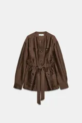 Blazer marrón de cuello redondo y manga larga, confeccionado con mezcla de lino. Cuenta con bolsillos de plastrón en el delantero, cintura ajustable con cinturón del mismo tejido y cierre frontal con botones.