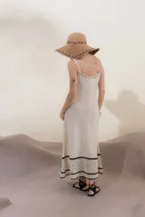Vestido tejido de algodón y poliéster color crema, de corte largo y tirantes finos. Presenta un borde inferior con terminación artesanal en crochet con dibujo de calados en hilo negro.