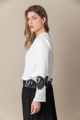 Blusa color marfil de seda con incrustaciones de cruni negro, mangas amplias y cuello cerrado con abertura.