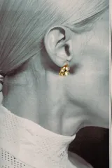 Par de aros dorados con textura irregular, adornados con tres perlas blancas y un pequeño cristal brillante.