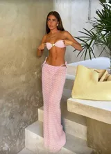 Conjunto de bikini negro con lunares blancos, compuesto por un corpiño bandeau con detalle de hebilla dorada y una falda larga de tul transparente con abertura lateral y lazos ajustables en la cadera.