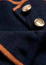 Jersey de punto fino en color azul marino, con cuello perkins y cierre de botones decorativos efecto joya en el hombro. Presenta un diseño recto de manga larga con detalles de ribetes en tono contrastante.