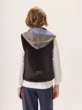 Chaleco con capucha, presenta una espalda de pelo sintético en color marrón oscuro con etiqueta de cuero negra y una capucha de tela tipo denim azul. Diseño original con mezcla de texturas.