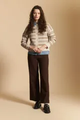 Cardigan corto de tejido jacquard con diseño geométrico en tonos beige y crema, con cierre frontal de botones y cuello redondo.